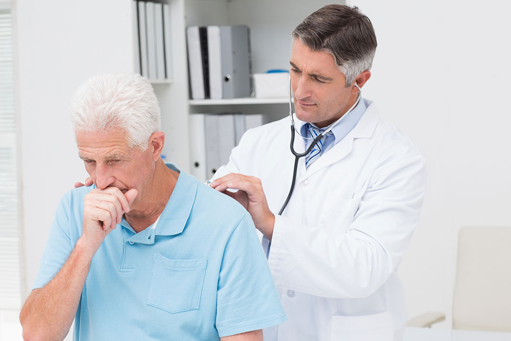 Male doctor examining coughing senior patient in clinic