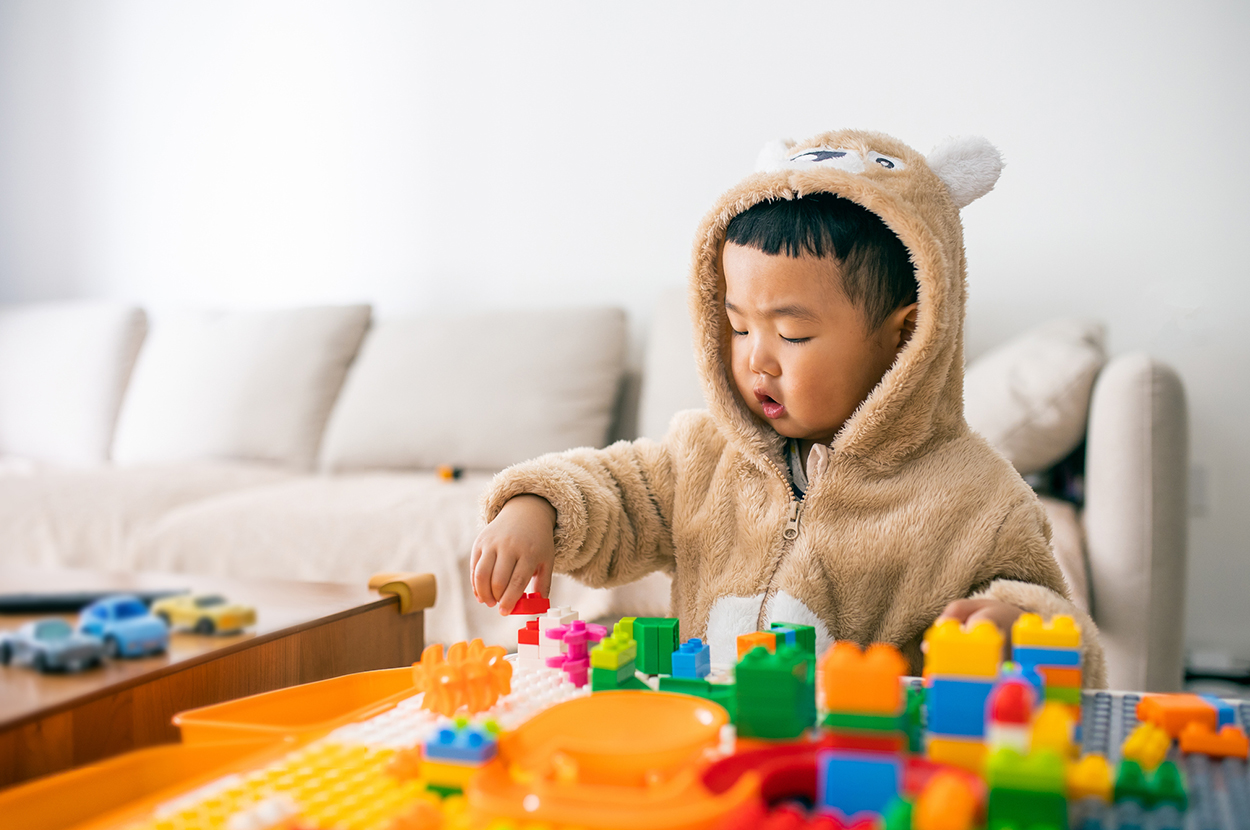 Toddler with bear coat playing blocks