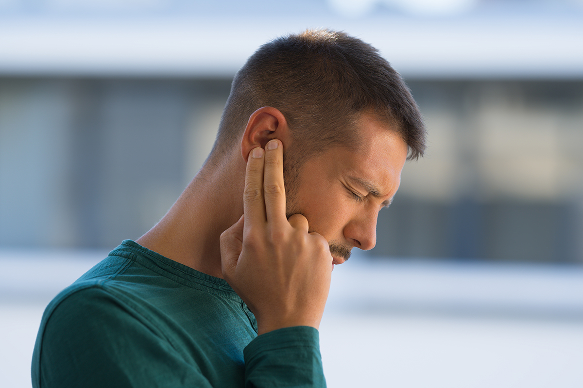 Man touching his ear because of strong earache or ear pain